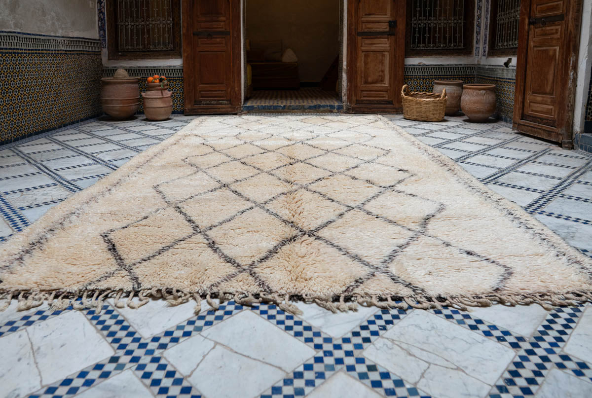 Beige and brown geometric patterned rug on a tiled floor with wooden doors in the background