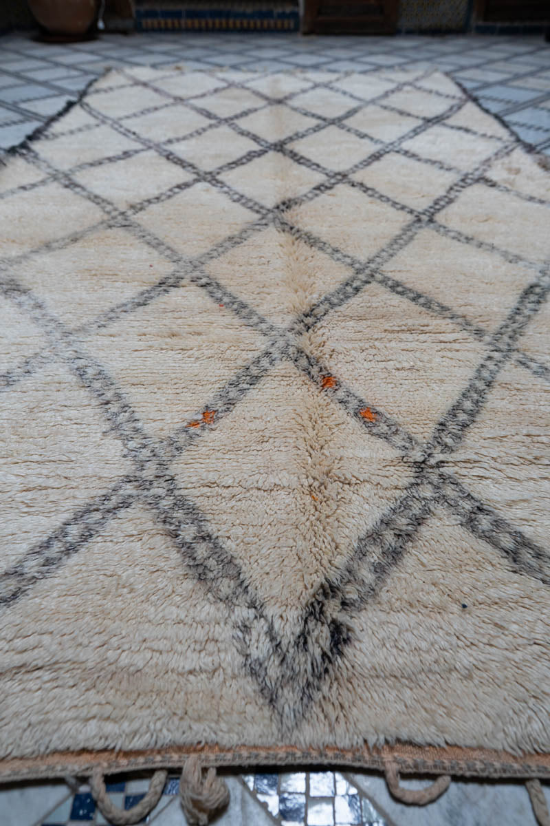 Marokkolainen vintage Beni Ouarain matto perinteikkäässä marokkolaisessa tilassa, jossa puiset käsintehdyt ovet, saviruukkuja ja koreja
