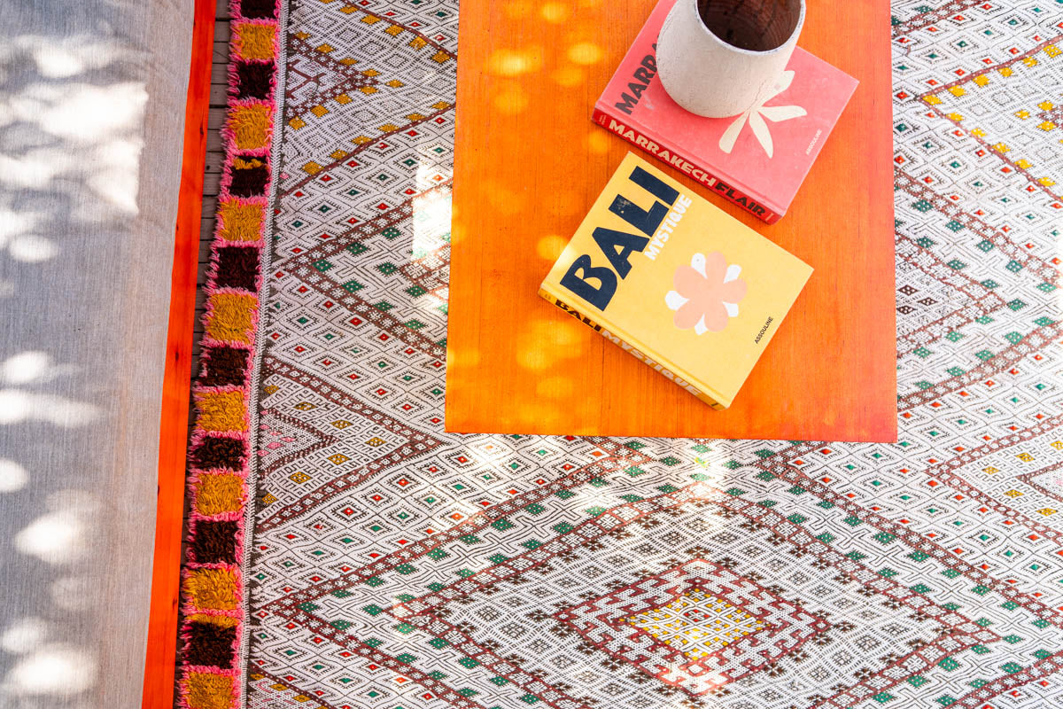 Colorful patterned moroccan kelim rug with a small table and books on top