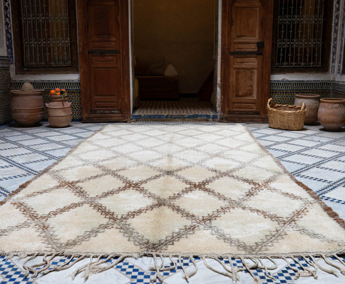 Decorative Moroccan Beni Ouarain rug with geometric pattern on a checkered floor in a traditional setting.