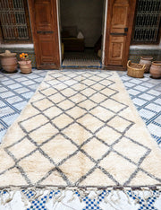 Natural white diamond patterned rug on a blue and white checkered floor with wooden doors in the background.