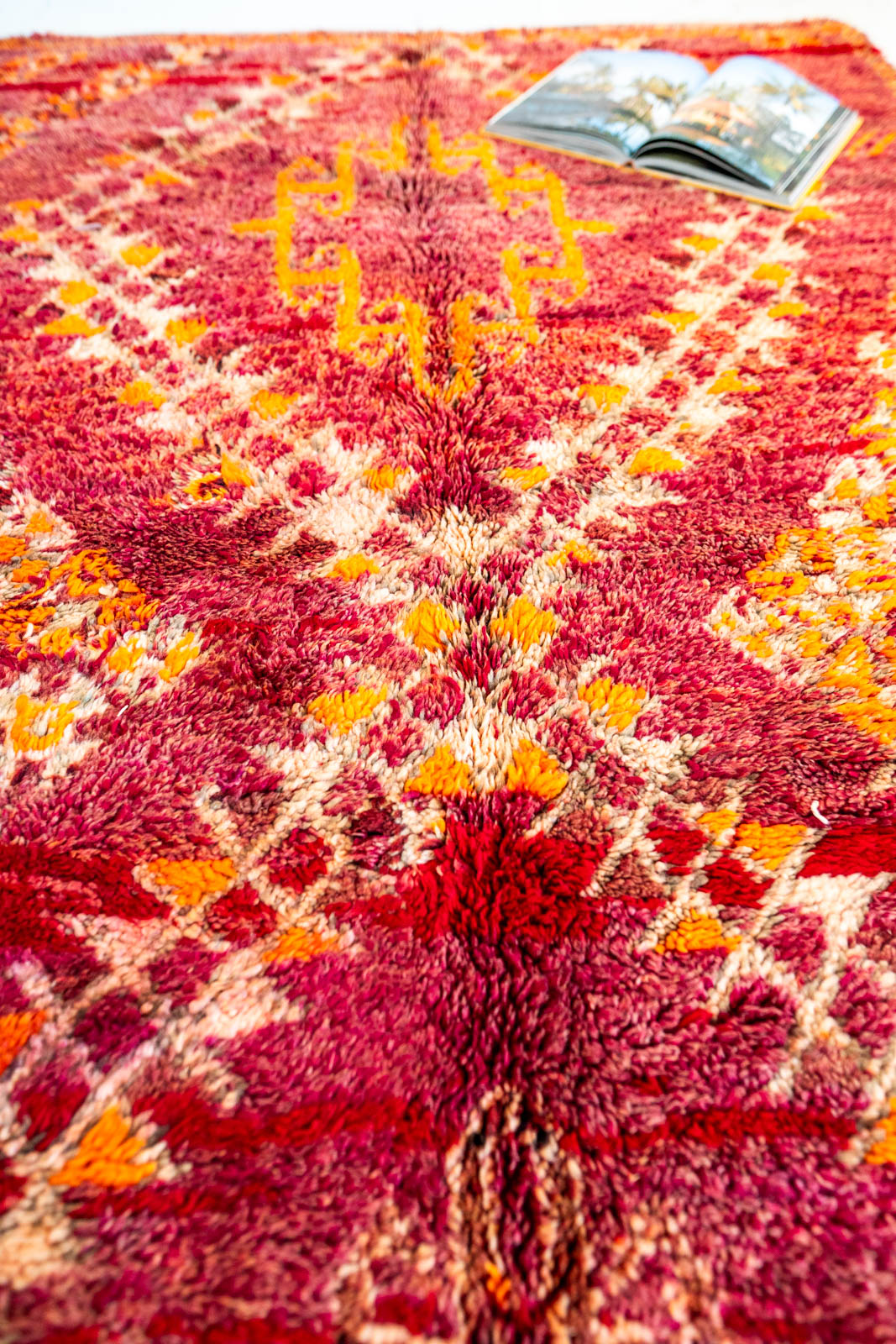 Decorative red rug with geometric pattern and open book on top